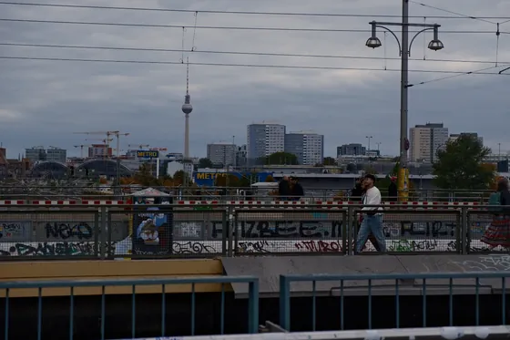 Berlin's television tower on a grey skyline, above graffitied railings and tram wires